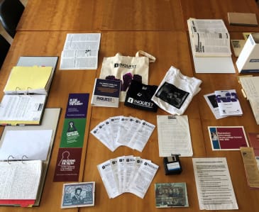 Collection of archive materials laid out on a table including leaflets, flyers, tshirts